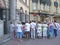 Crowd of tourists listening to guide during excursion around city