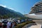 a crowd of tourists near the pier with a cruise ship on street of Kotor city Montenegro, a bright sunny day, mountains and palm