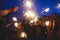 A crowd of young happy people with bengal fire sparklers in their hands during birthday celebration