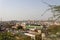 A crowded city shot from a high angle view point with Acacia tree branches in front and blue sky in background.