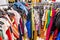 Crowded clearance section in a clothing store, with various colorful garments placed tightly on racks in no particular order; fast