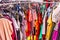 Crowded clearance section in a clothing store, with various colorful garments placed tightly on racks in no particular order; fast