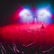 A crowded concert hall with scene stage in red lights, rock show performance, with people silhouette, dance floor  during a concer