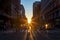 Crowds of diverse people walk across a busy intersection on 5th Avenue in New York City with sunlight background