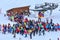 Crowds of skiers and snowboarders queue by chair ski lift station of Gorky Gorod mountain ski resort on winter day