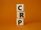 CRP - C-Reactive Protein Test symbol. Wooden cubes with word CRP. Beautiful orange background. Medical and C-Reactive Protein Test