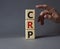 CRP - C-Reactive Protein Test symbol. Wooden cubes with word CRP. Doctor hand. Beautiful grey background. Medical and C-Reactive