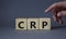 CRP - C-Reactive Protein Test symbol. Wooden cubes with word CRP. Doctor hand. Beautiful grey background. Medical and C-Reactive