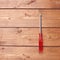 Cruciform screwdriver with the red handle on wooden surface