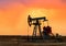 Crude oil pump jack at oilfield on atmospheric sunset backround. Fossil crude output and fuels oil production. Oil drill rig and