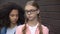 Cruel black student bullying caucasian schoolgirl eyeglasses, hitting shoulder