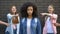 Cruel group of teens pointing fingers at curly afro-american schoolgirl, racism