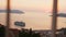Cruise liner standing in bay in distance against backdrop of orange sunset over sea. Panorama of small tourist town with