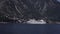 Cruise ship enters a port on a background of mountains.