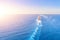 Cruise ship liner goes into horizon the blue sea leaving a plume on the surface of the water seascape during sunset. Aerial view,