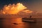 Cruise ship sailing in the sunset with white clouds over the Caribbean sea.