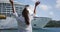 Cruise ship travel concept. Woman waving hands goodbye at cruise ship leaving. Caribbean luxury travel vacation concept