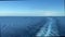 A cruise ship wake in the Atlantic Ocean on a sunny day with dark blue water and clear skies