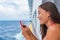 Cruise ship woman using mobile phone on travel vacation at ocean. Asian girl texting sms on wifi on tropical holidays. Internet on