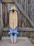 Cruising longboard against a rustic wooden gate