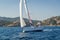 Cruising sailboat sailing near Sardinia island shores.