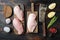 Crumbed uncooked chicken breast ingredient with butcher knife on dark wooden background, top view