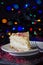 Crumble cheesecake sprinkled red sugar crystals. Royal cheesecake. Blurred lights background.