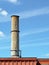 Crumbling concrete smokestack against a blue sky