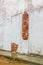 Crumbling wall on rainy day - plaster cracking off exterior building wall and laying in piles on wet grungy sidewalk below -