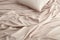 Crumpled beige bed linen with pillows and blankets