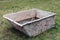 Crumpled rusty iron container for mixing liquid plaster on a grass lawn near a village house