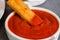 Crunchy breaded fish stick made from wild caught Alaskan Pollock dipped in ketchup close-up on the kitchen table