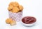 Crunchy chicken popcorn bites in kids paper cup for fast food meals on white background with ketchup