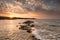 Crushing waves on jagged rocks during sunset