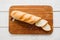 Crusty baguette on wooden board flat lay