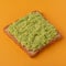 Crusty toast with mashed avocado on orange background