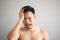 Cry and sad face of Asian man in topless portrait isolated on gray background