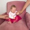 Crying baby sitting in the chair. Hands of grandmother holding child sitting in the chair. Negative child emotion