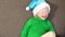 crying cute little girl 5-6 years old in a green sweater and a santa claus hat sitting on the sofa,