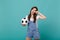 Crying disconcerted young woman football fan support favorite team with soccer ball wiping tears isolated on blue