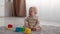 Crying Infant Boy Sitting On Floor In Living Room With Toys Around