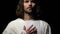 Crying Jesus Christ in crown of thorns holding hand near heart, kindness, faith