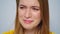 Crying woman smiling at camera on grey background in studio. Sad and happy