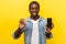 Cryptocurrency mobile application. Portrait of excited joyous man holding cellphone and golden bitcoin. isolated on yellow