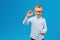 Cryptocurrency and modern finance. Cheerful boy in eyeglasses holding golden bitcoin in studio on blue background