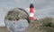 Crystal ball with an upside down lighthouse and the lighthouse next to it in the background