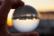 Crystal ball wih recletion of LimassolÂ´s harbour at sunset. Glass/Lens ball holding in hand with golden city lights and sea in