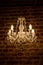 Crystal chandelier, antique lamp on the background of the brown brick wall.
