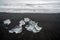 Crystal clear ice chunks washed up on the black lava sand by the waves on diamond beach