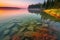 crystal-clear lake at sunrise, with stunning yellow and pink hues